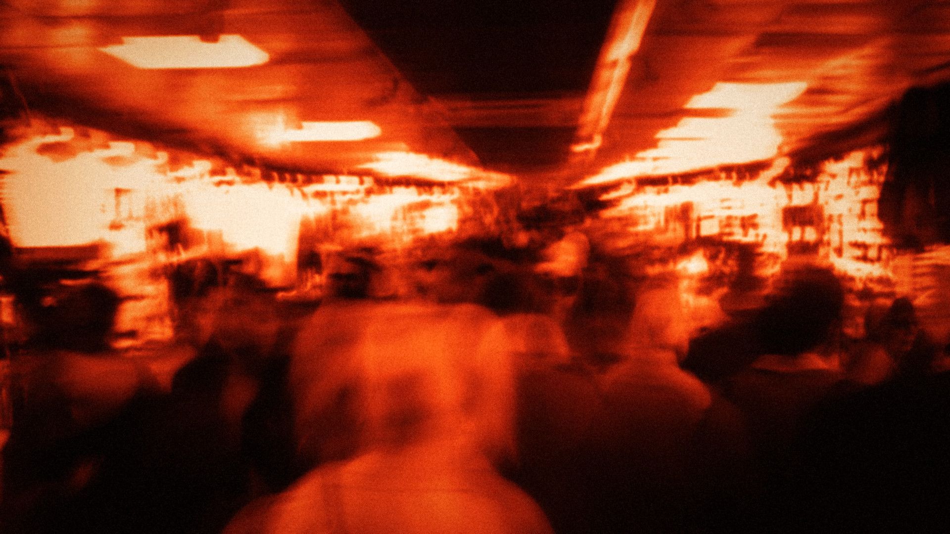 A crowd moving through a bright hall, blurred