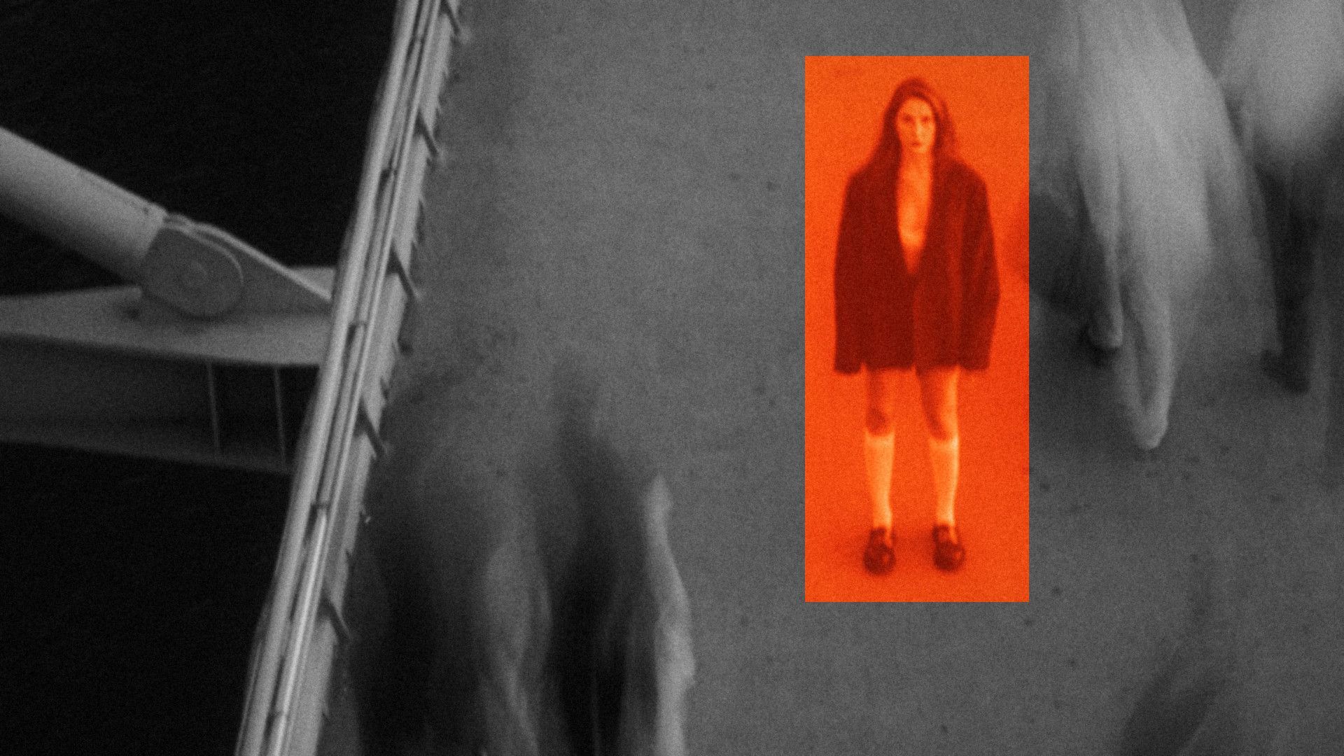 A woman standing still on a busy bridge, framed in orange